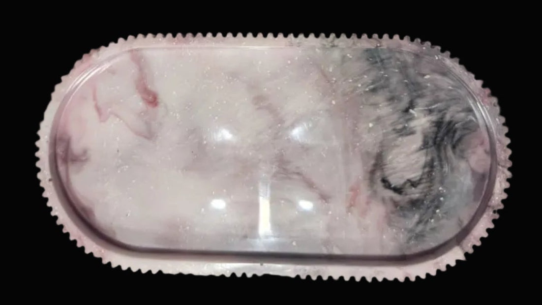 An oval-shaped clear resin tray with a pink and white marble pattern and a textured pink border