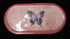 Small pink glitter oval tray with a butterfly in the center set on a white background for visual affect.