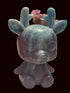 A small carved figurine of a deer or rabbit-like creature with antlers, shown sitting on a textured tablecloth in a home interior. The object has a marbled coloration with blue-green on top and purple-gray below.