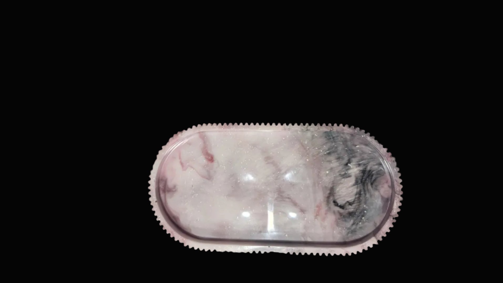 An oval-shaped clear resin tray with a pink and white marble pattern and a textured pink border